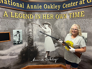 PWoman holding a rifle in front of a museum exhibit